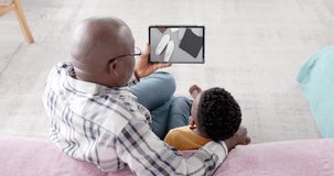 African american grandfather and grandson using tablet, online shopping for clothing, slow motion. Retail business, sale and digital interface digitally generated video.