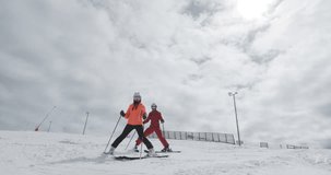 Female and male skiers standing and skiing on slopes. Couple having fun together. Ski run 2 clip 1of2. Recorded on cinema camera 50fps.