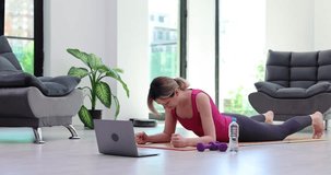 Woman getting plank in front of laptop at home 4k movie. Fitness online concept