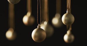 Video of gold baubles christmas decorations with copy space on black background. Christmas, decorations, celebration and tradition concept.
