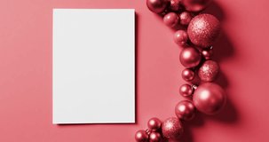 Video of christmas decorations and white card with copy space on red background. Christmas, decorations, tradition and celebration concept.