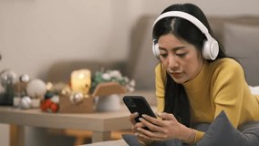 Smiling woman with headphones listening to music, relaxing on sofa in Christmas living room - Powered by Shutterstock - Get 15% off with code: PIKWIZARD15