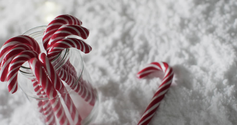 Video of christmas candy canes in jar and copy space on snow background. Christmas, baking, decorations, tradition and celebration concept.