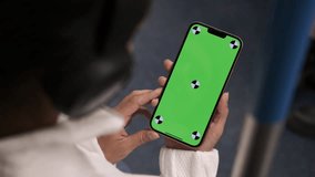 Woman using smartphone with vertical green screen display watching movie, video content on train. Browsing social network, news. Girl using smartphone internet surfing communication online. Close up