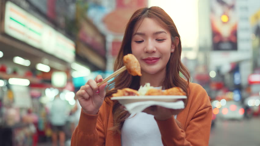 Happy young tourist Asian woman enjoy and fun traditional asian street food at Bangkok Chinatown, Female shopping and eating street food on summer holiday vacation. Royalty-Free Stock Footage #1109921919