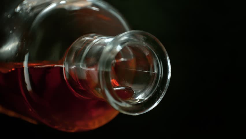 Super Slow Motion Shot of Camera Following Alcohol from Bottle into Glass With Ice at 1000fps.