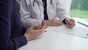 Doctor and patient sitting at the table and discussing something. The pediatrician in a blue dotted blouse and white medical coat is gesturing actively. Medicine concept