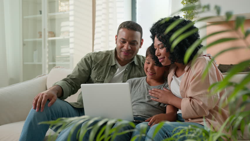 Happy African American family mom dad and teen son use laptop webcam distance video call multiracial parents little boy child wave hands smile greeting relatives remote communication on device at home Royalty-Free Stock Footage #1109927119
