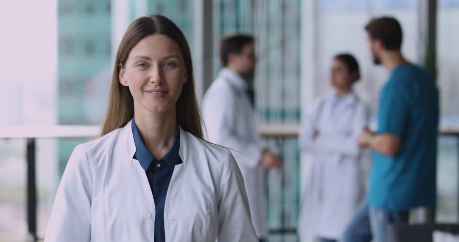 Attractive female physician GP in white uniform posing in modern clinic office, provide professional services, satisfied with career. Vocation, mission, profession. Reliable medical worker portrait Royalty-Free Stock Footage #1109930319