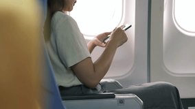 Businesswoman female passenger of airplane using networks via smartphone wifi on board, young girl sending message on phone solo traveling by plane. Traveling technology concept - Powered by Shutterstock - Get 15% off with code: PIKWIZARD15
