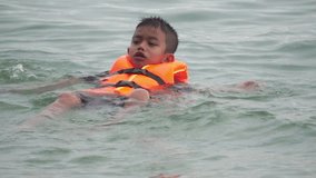 Boy wearing life jacket playing in water at swimming sea, If there is an unexpected danger at sea
