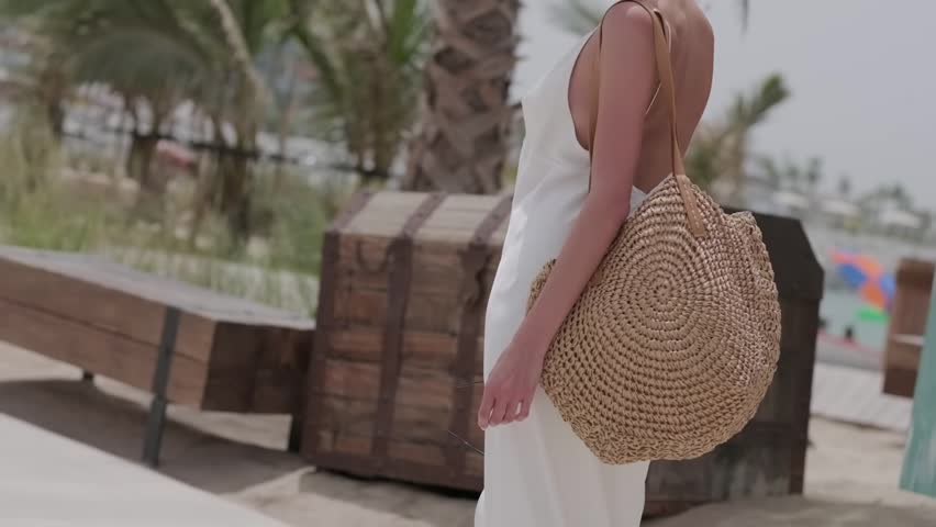 Young woman in white light dress standing on the sea promenade