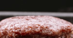 Beef cutlet for halal burger fried in frying pan. Sprig of rosemary placed on cutlet during frying. Cinematic advertisement video burger cooking. Close-up of delectable cutlets frying to perfection