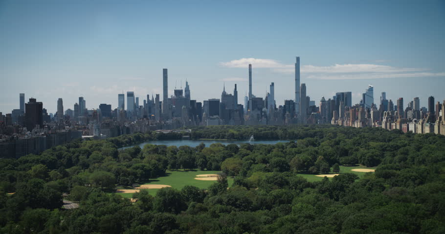 Aerial Helicopter Footage Over Central Park with Nature, Trees, People Having Picnic and Resting on a Field Around Manhattan Skyscrapers Cityscape. Beautiful Sunny Day. Slow Motion Footage