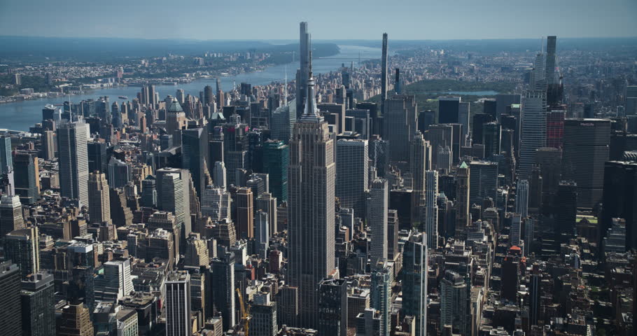 Aerial Footage of New York City and Manhattan Panoramic Skyline with Iconic Empire State Building. Helicopter View of the Cityscape from Above with Towering Tourist Attraction