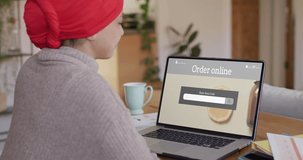 Biracial woman using laptop, online shopping for beauty products, slow motion. Retail business, sale and digital interface digitally generated video.