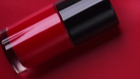 Red nail polish bottle rolling over bright red background, top view. Gel nailpolish, shellac UV, bottle with brush, varnish, manicure concept, Beauty salon. Glass bottle close up. Nail care product - Powered by Shutterstock - Get 15% off with code: PIKWIZARD15