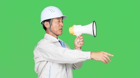 Asian middle-aged man wearing work clothes shouting through a bullhorn in front of a green background for chroma key composition. Factory worker. Construction engineer. - Powered by Shutterstock - Get 15% off with code: PIKWIZARD15