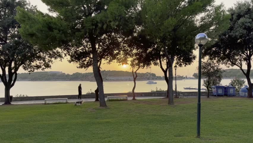 Sunset in Vouliagmeni over grass area with sea in the background