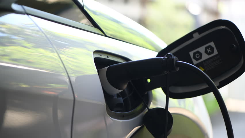 Man unplugs charging cable electric vehicle. Driver removes charger of his electric vehicle. Save ecology alternative energy sustainable of future