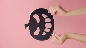 Vertical video of female hands holding big black paper spooky pumpkin, isolated over pink color background wall with copy space for promotion content or design. Concept for Happy Halloween Holiday - Powered by Shutterstock - Get 15% off with code: PIKWIZARD15