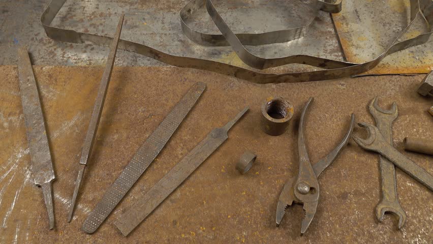 Old rusty instruments open end wrench, pliers, rasp and others lie on the rusty sheets metal