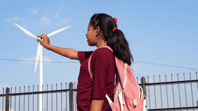 Little Indian girl shooting a video clip and showing catch windmill turbine in footage. Kids photography and windmill.