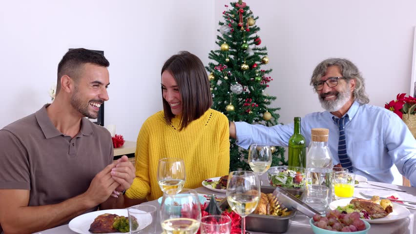 Young beautiful adult couple making an important announcement at family Christmas meal. Group of people celebrating exciting good news at dinner xmas celebration: pregnancy or wedding | Shutterstock HD Video #1109968245