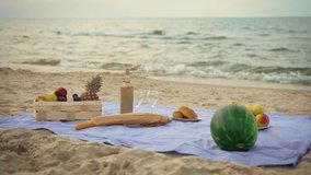 Front view of decorations for outdoor picnic, blanket on sand ocean beach with food, alcohol wine drink, fruits in basket in summer vacation. Party outdoors. Enjoying time together concept - Powered by Shutterstock - Get 15% off with code: PIKWIZARD15