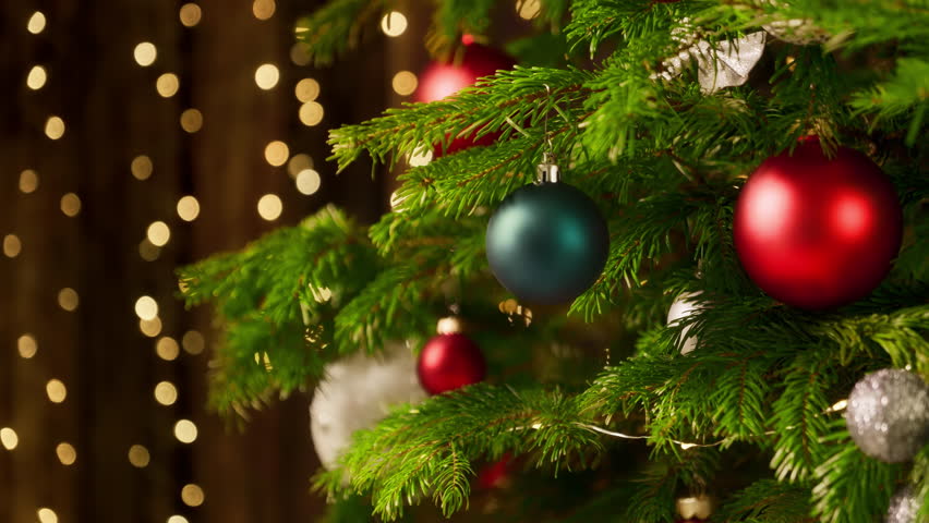 Decorated Christmas tree closeup, with sparkling bokeh lights on the dark wooden background, the camera tilts up
 | Shutterstock HD Video #1109973457