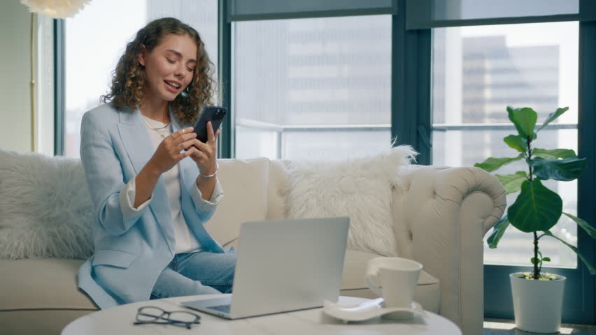 Online shopping concept. Super excited young woman using smart phone surfing social media, making online purchases sitting on sofa. Stylish lady spending time at home with cell gadget technology 4K Royalty-Free Stock Footage #1109975723