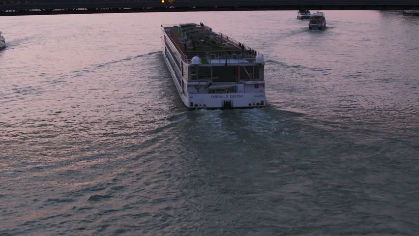Fly over sightseeing boat passing under bridge. No people on top deck in twilight time. Budapest, Hungary