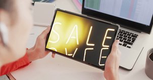 Caucasian woman at desk using tablet, shopping online during sale, slow motion. Retail business, sale, communication and digital interface digitally generated video.