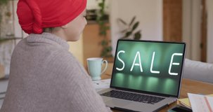 Biracial woman using laptop, online shopping during sale, slow motion. Retail business, sale and digital interface digitally generated video.