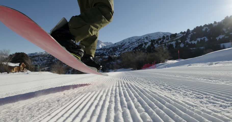 Professional snowboarder performs spectacular trick at ski resort. Sportsman athlete snowboarder pushes off snow, spinning in air around axis, deftly lands. Professionalism of experienced snowboarder
