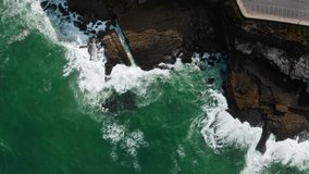 Aerial view of the beautiful ocean rocky shore with rolling waves.  Drone view over surface of the water along the rocky shore. Drone is flying over rolling ocean waves to the rocky shore.
