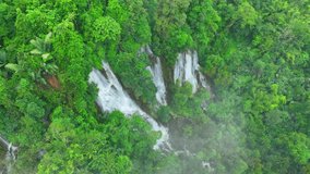 The drone's perspective reveals a breathtaking sight: a grand waterfall concealed within a vibrant tropical rainforest, a verdant paradise hidden from the world. Wild woods, nature's art. Thailand.
