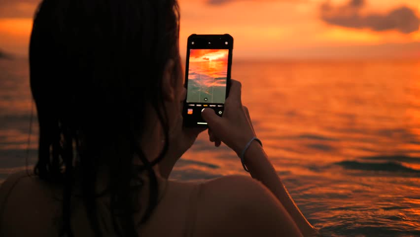 Young Attractive Tourist Girl Taking Photos of Amazing Colourful Sunset Sky. Female in Bikini Making Photos with Smartphone near Beach. High Quality 4K Slowmotion Tropical Life. Phuket, Thailand.