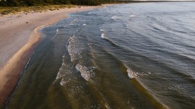 Sea waves at sunset on the Baltic Sea. Sandy beach in Kolobreh. Taken from a drone. Kołobrzeg is a city in Poland. Sea with beautiful waves on a sunny summer day. 4k Time lapse 
