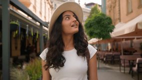 Excited amazed happy smiling young Indian Arabian ethnic woman girl female student tourist traveler walking sightseeing laughing looking at camera on city street cheerful smile holidays tour outside