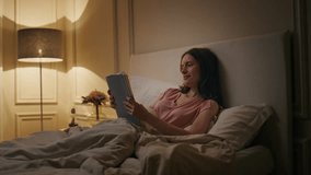 Peaceful woman reading book in evening home. Smiling reader enjoying novel rest in cozy bed on weekend night. Calm relaxed female chill studying late in lamp light. Favourite literature hobby concept. - Powered by Shutterstock - Get 15% off with code: PIKWIZARD15