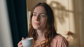 Dreamy girl drinking coffee in morning sunlight closeup. Peaceful gorgeous model holding cup taking sip at cozy home. Beautiful smiling woman enjoying chill atmosphere. Perfect weekend relax concept - Powered by Shutterstock - Get 15% off with code: PIKWIZARD15