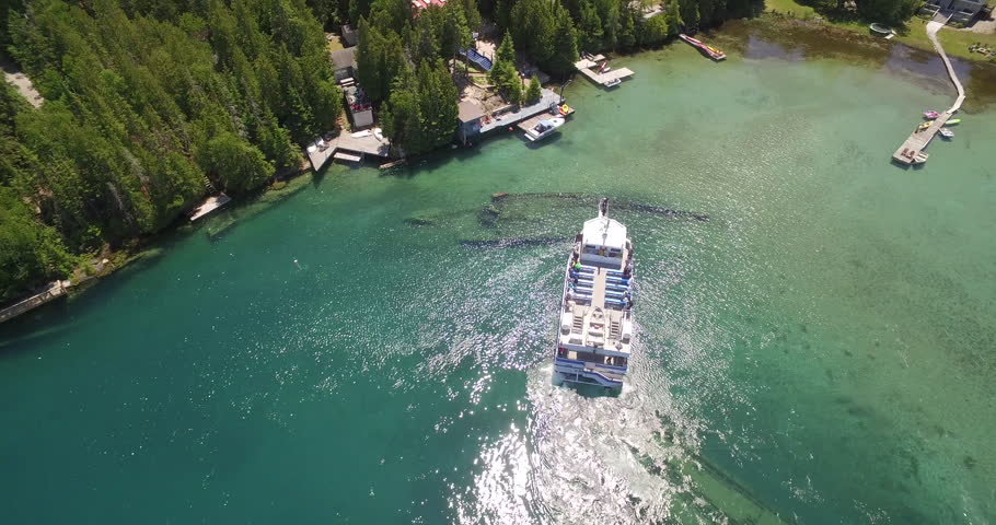 An aerial top view footage of a boat on the glowing water at the harbor in Tobermory, Ontario, Canada Royalty-Free Stock Footage #1110019651