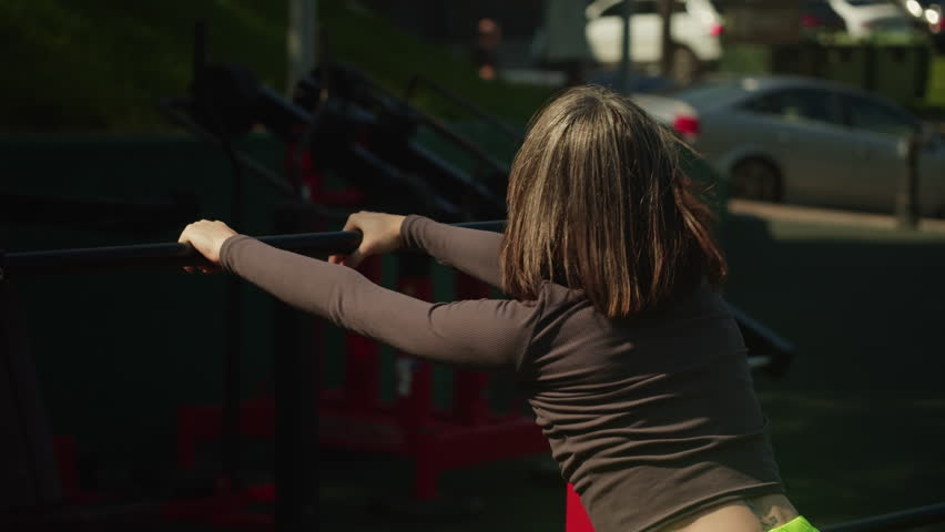 Young woman doing stretching on the ground among sports equipment. Doing Yoga on the sport ground outdoors