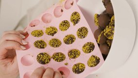 A woman squeezes prepared chocolates into a bowl with her hands from a silicone mold. Close-up. Vertical video