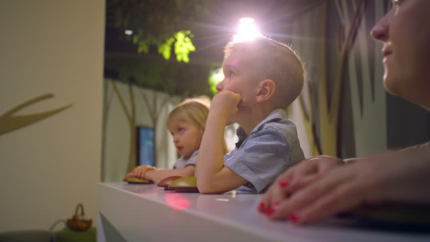 Two cute little children enjoying with their mother during the natural history museum visit, having fun in an interactive exhibition, close up shot.