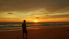 .A man uses a drone to take photos at the beach..Amazing Golden yellow sky during sunset..smooth wave hit on the beach..stunning reflection of colorful cloud in sweet sky on sea surfect.sky texture.