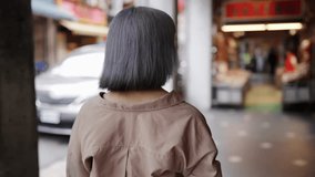 Slow motion video of a young Taiwanese woman with gray hair strolling through the old streets of Dihua Street.