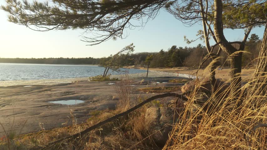 Hiker crossing shorling of Killbear Provincial Park on a cold early spring sunset