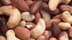 Vertical video. Closeup top view of mixed nuts over a wooden background. Peanuts, brazilian nuts, cashew, baru and almonds.